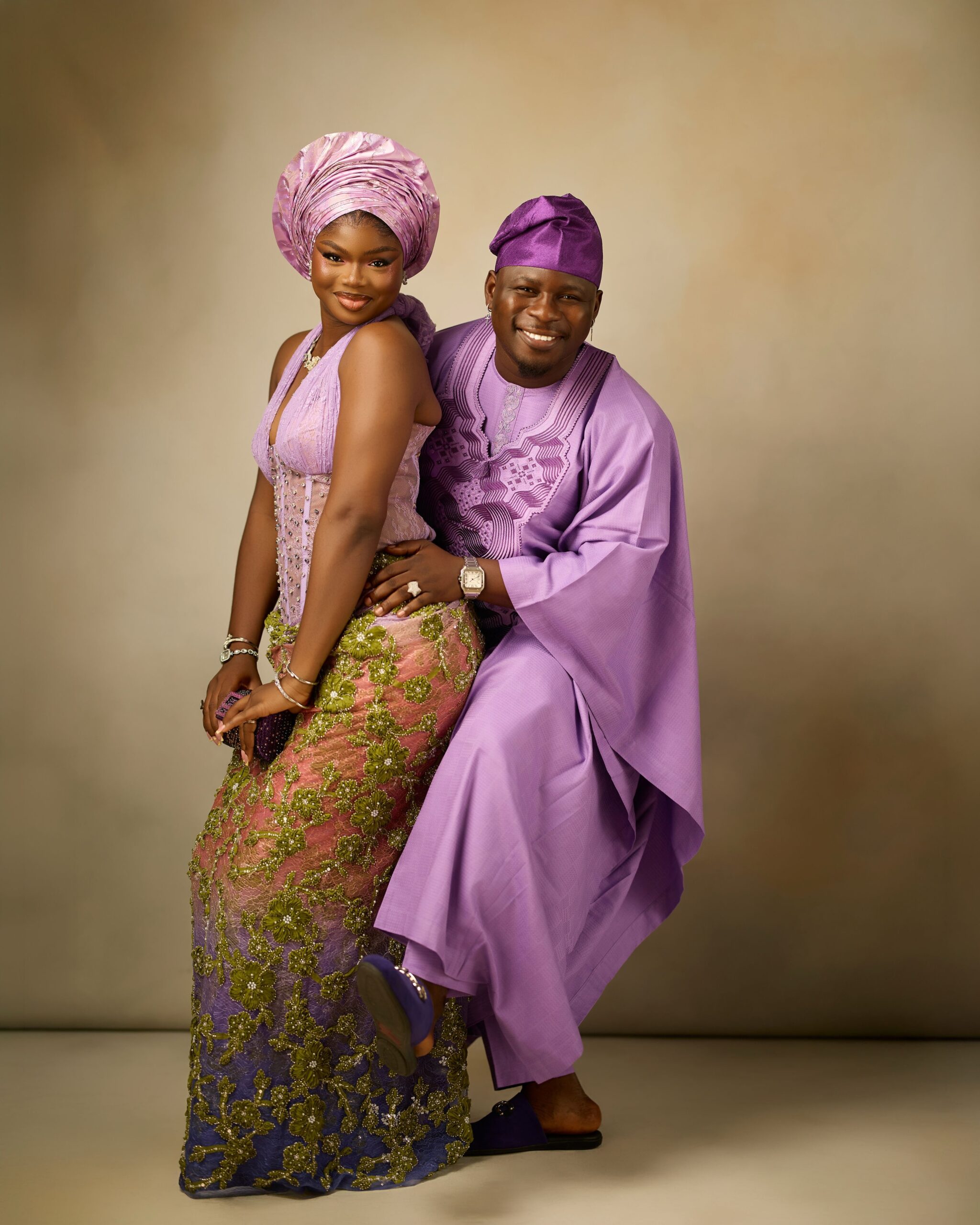 Kamo State holding his wife Olamide as they pose in matching lilac and purple traditional Yoruba outfits.