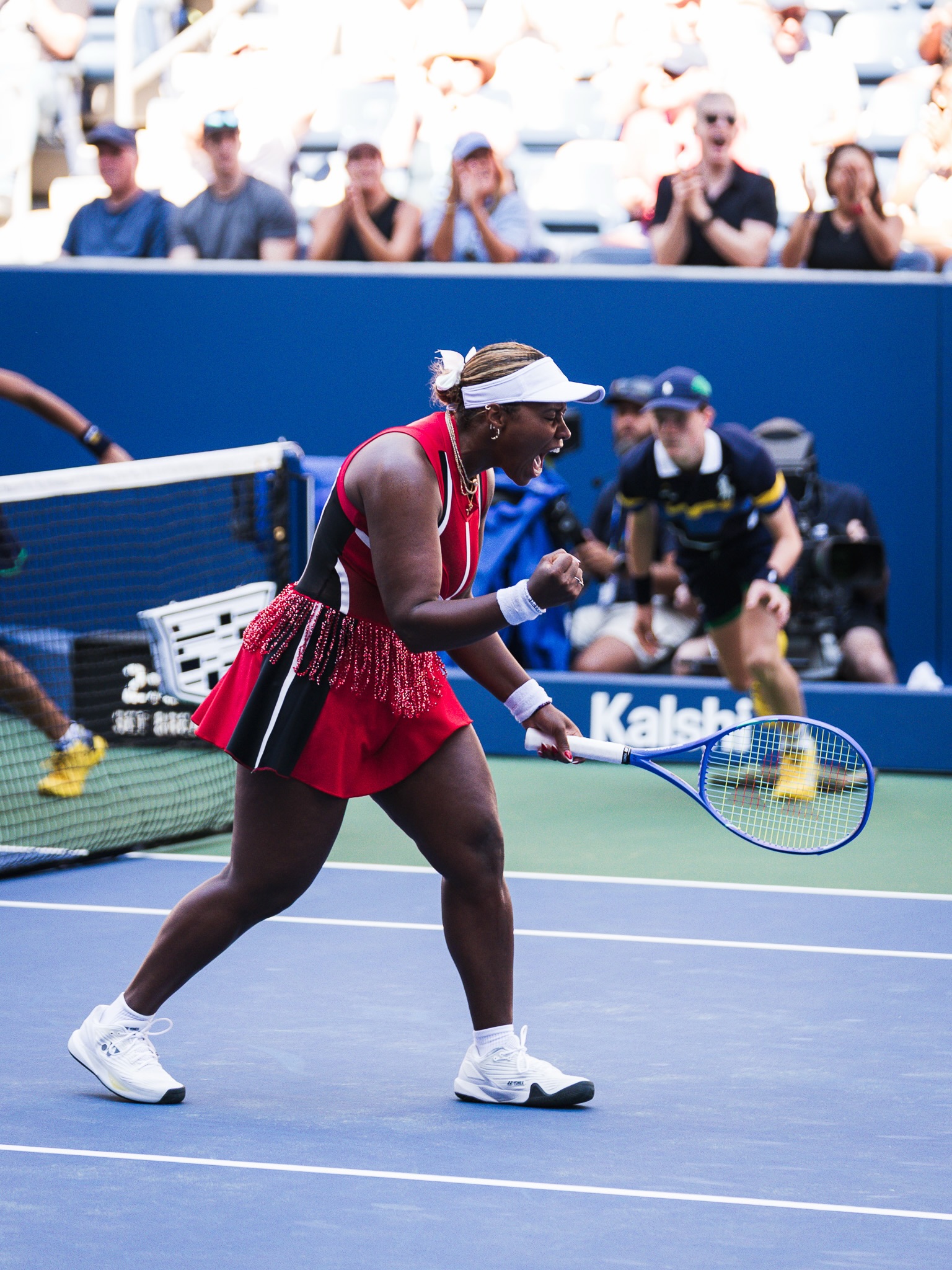 Taylor Townsend pumping her fist in celebration wearing a red outfit with fringe trim on court.