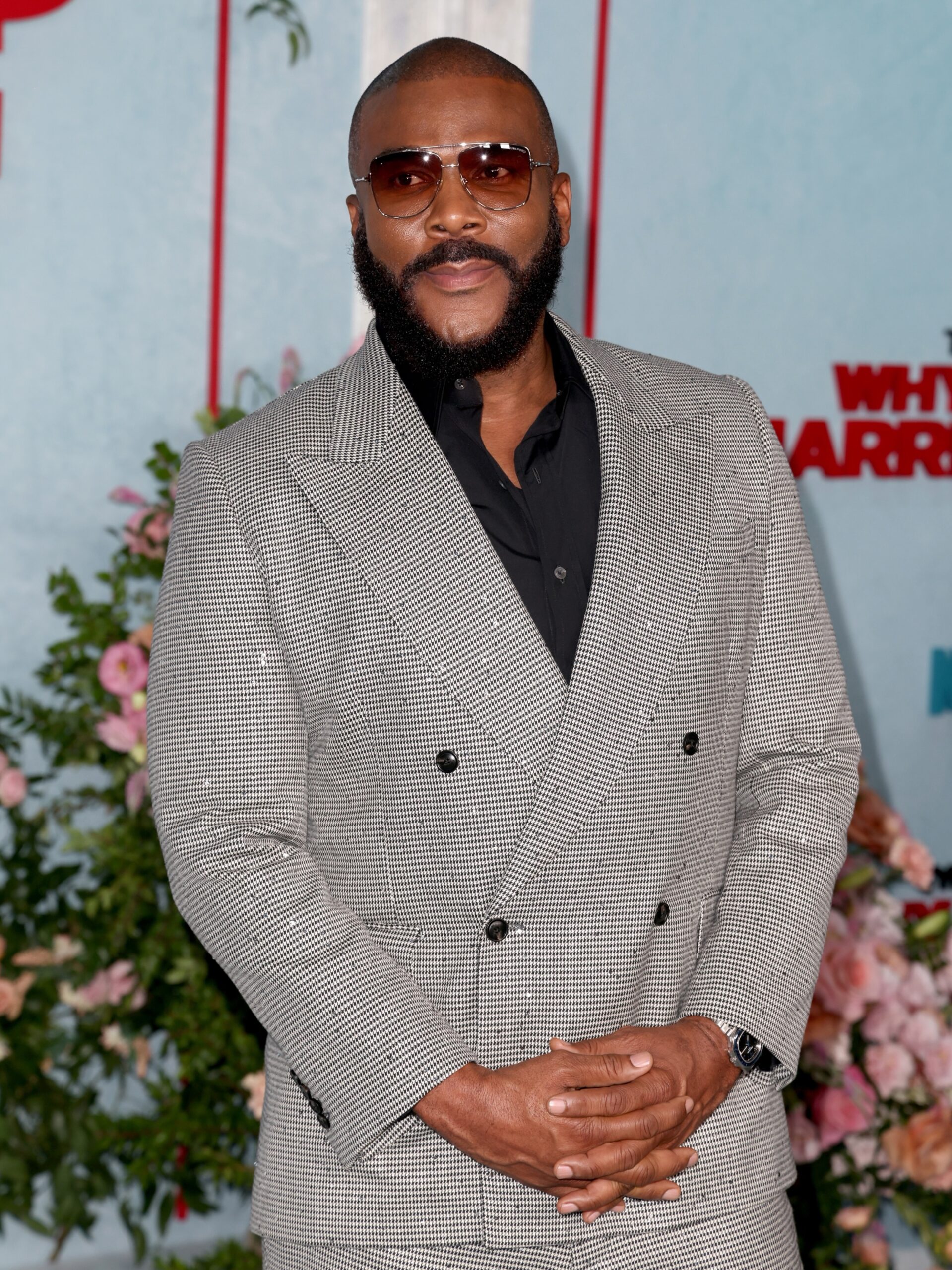 Tyler Perry wearing a houndstooth suit and tint glasses at a film premiere.