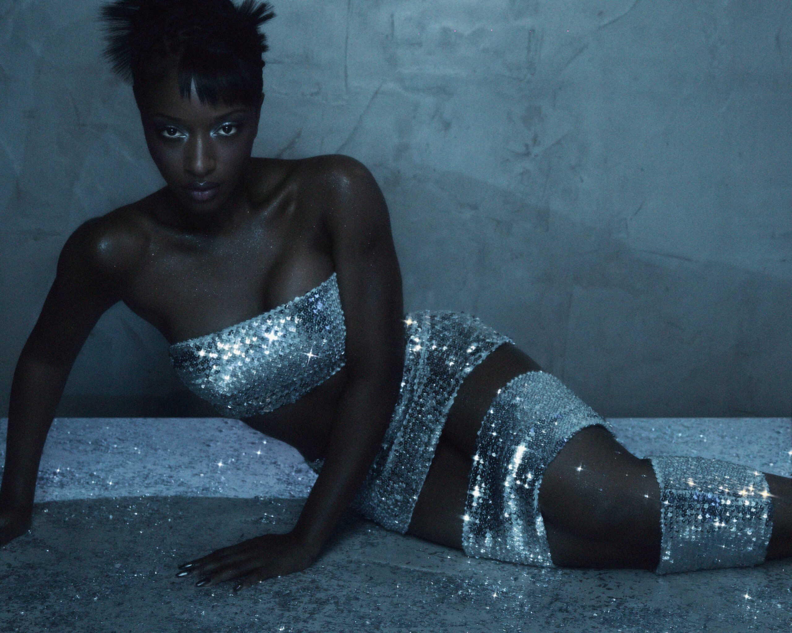 Ayra Starr wearing a silver sequin bandeau crop top with a matching cutout mini skirt and leg bands, photographed by Fernando Tomaz and styled by Jahulie for 66 GREENE Magazine.