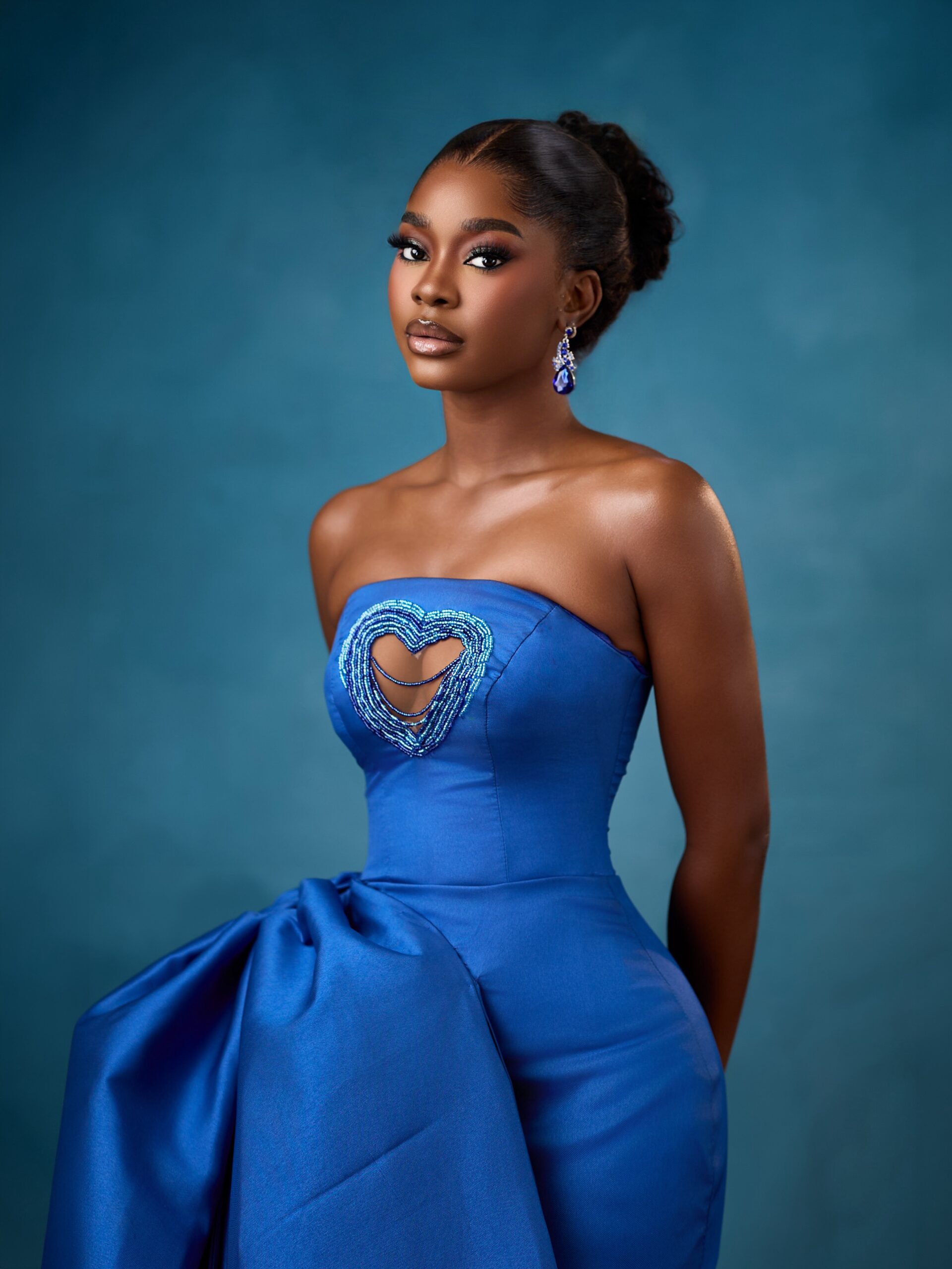 Dede Ashiogwu wearing a strapless royal blue dress with a heart-shaped beaded keyhole cutout and crystal teardrop earrings for the HookedOnTheFaminus white wedding.