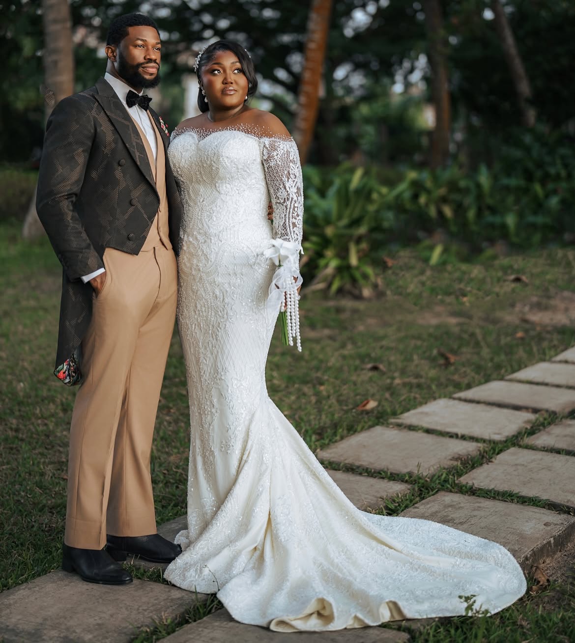 Nollywood actor Stan Nze in P.Aries tailcoat suit with wife Blessing Obasi Nzediegwu in Prudential lace wedding dress at vow renewal ceremony.
