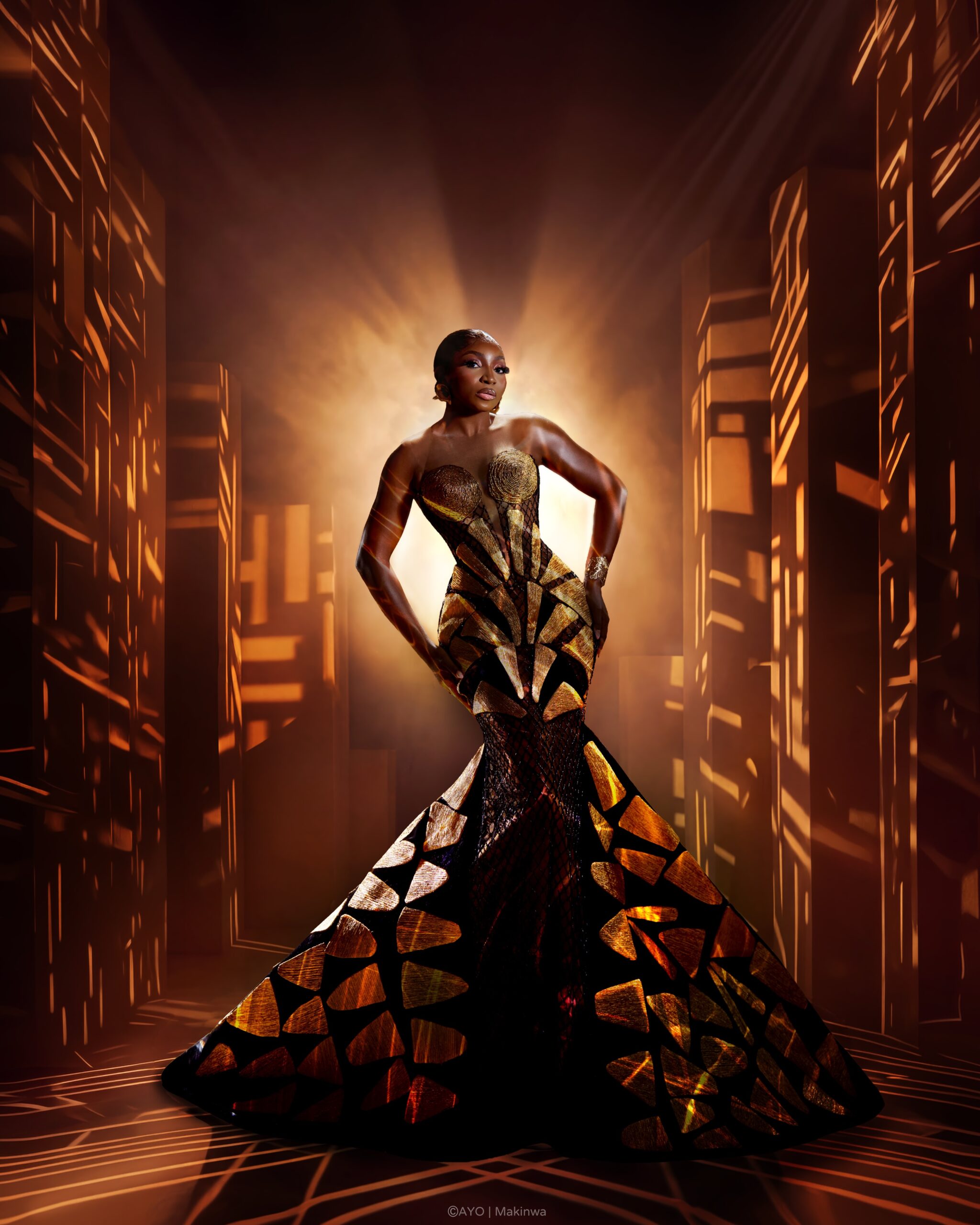 Omowunmi Dada in custom Somobysomo mermaid gown with geometric gold appliqués under dramatic studio lighting.