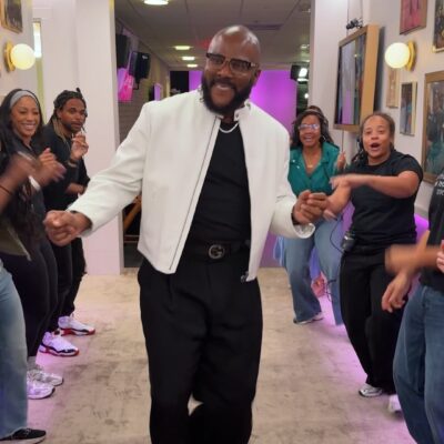 Tyler Perry dancing through The Jennifer Hudson Show Spirit Tunnel wearing a white leather jacket and Gucci belt.