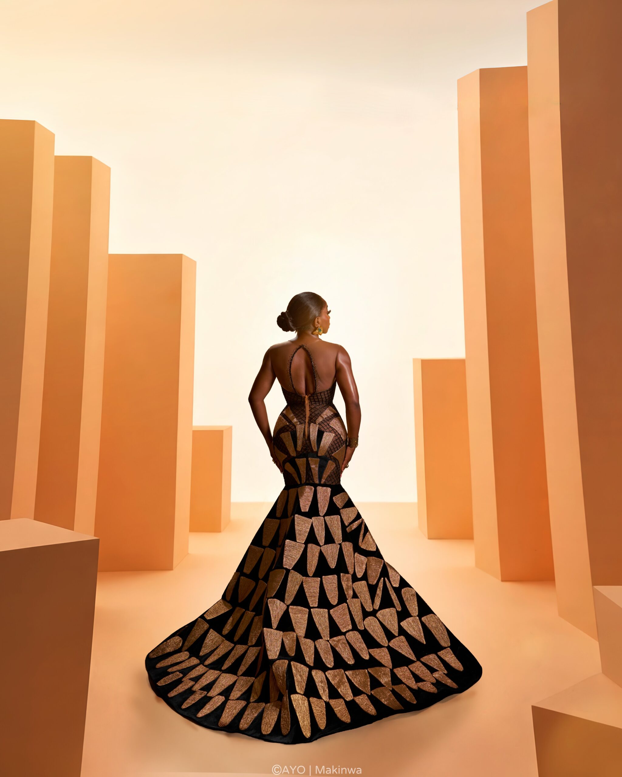 Omowunmi Dada wearing custom Somobysomo gown displaying low keyhole back and sweeping geometric mosaic train.