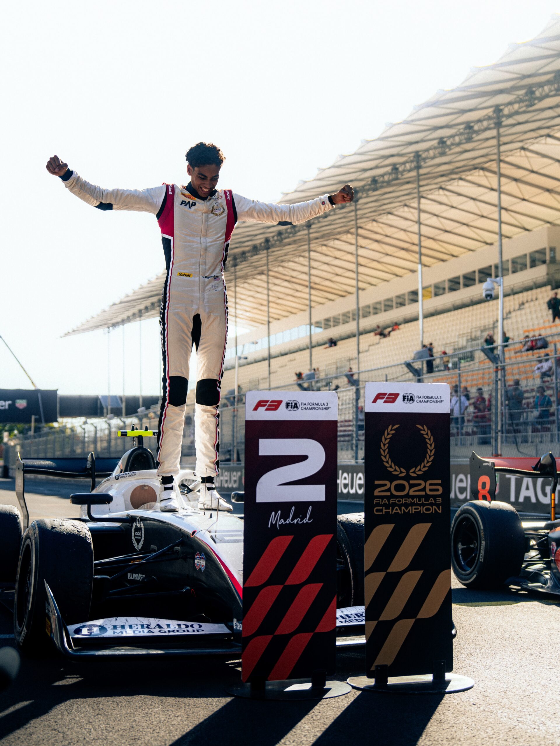 Ugo Ugochukwu standing on his Campos Racing car celebrating the 2026 FIA Formula 3 title win in Madrid.