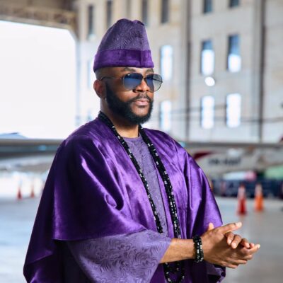 Ebuka Obi-Uchendu wearing layered black stone neck beads and a purple velvet agbada by D29 Africa.