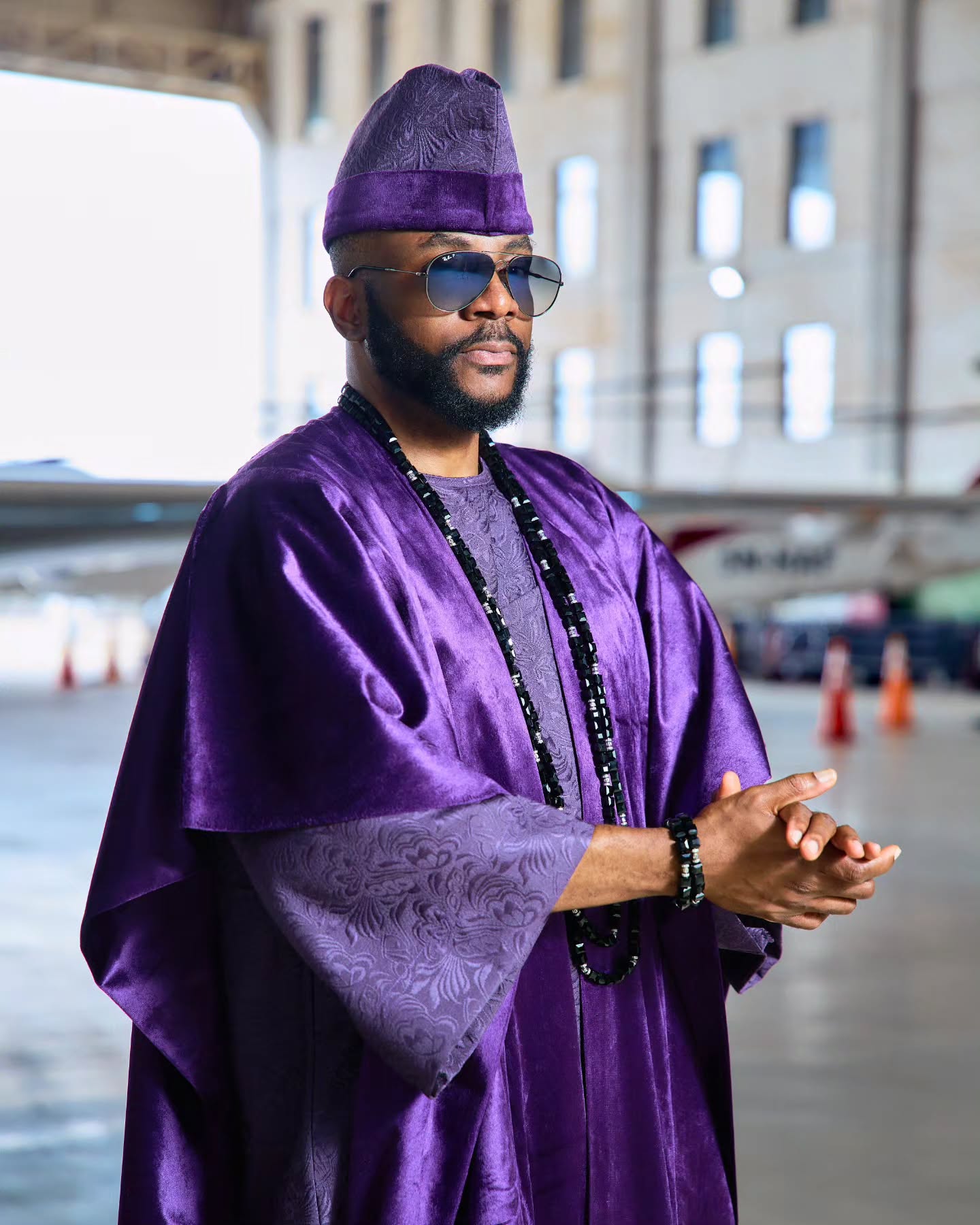 Ebuka Obi-Uchendu wearing layered black stone neck beads and a purple velvet agbada by D29 Africa.