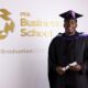 Taiwo Awoniyi smiling in academic cap and gown holding his diploma scroll in front of the PFA Business School graduation logo