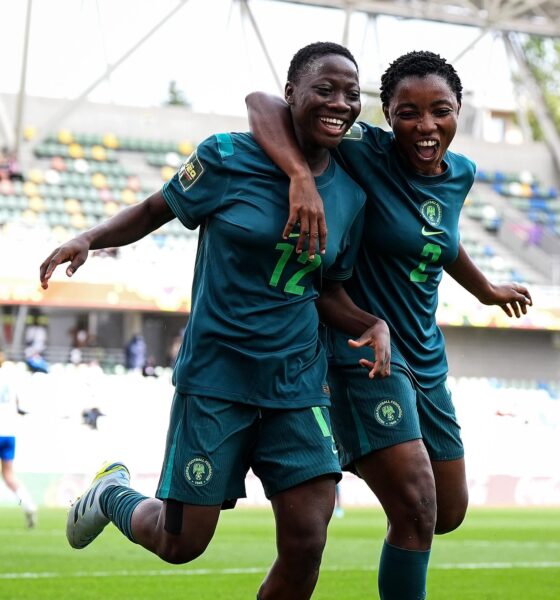 Two Nigeria Falconets players smiling and running side-by-side with arms around each other to celebrate a goal.