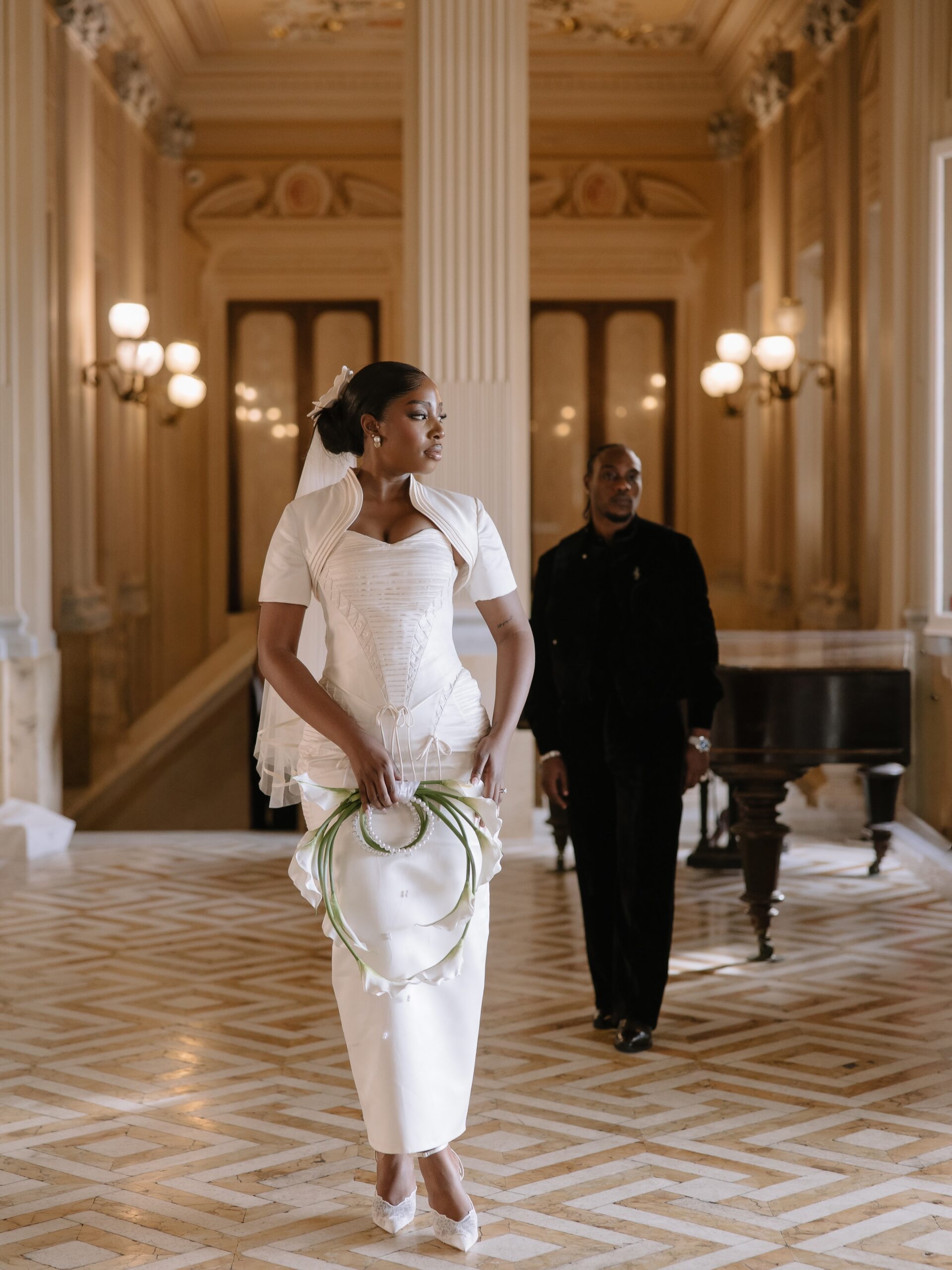 Ella wearing a Mazelle Bridal corset gown alongside LAX in a black velvet TJWHO suit in a Malta hall.