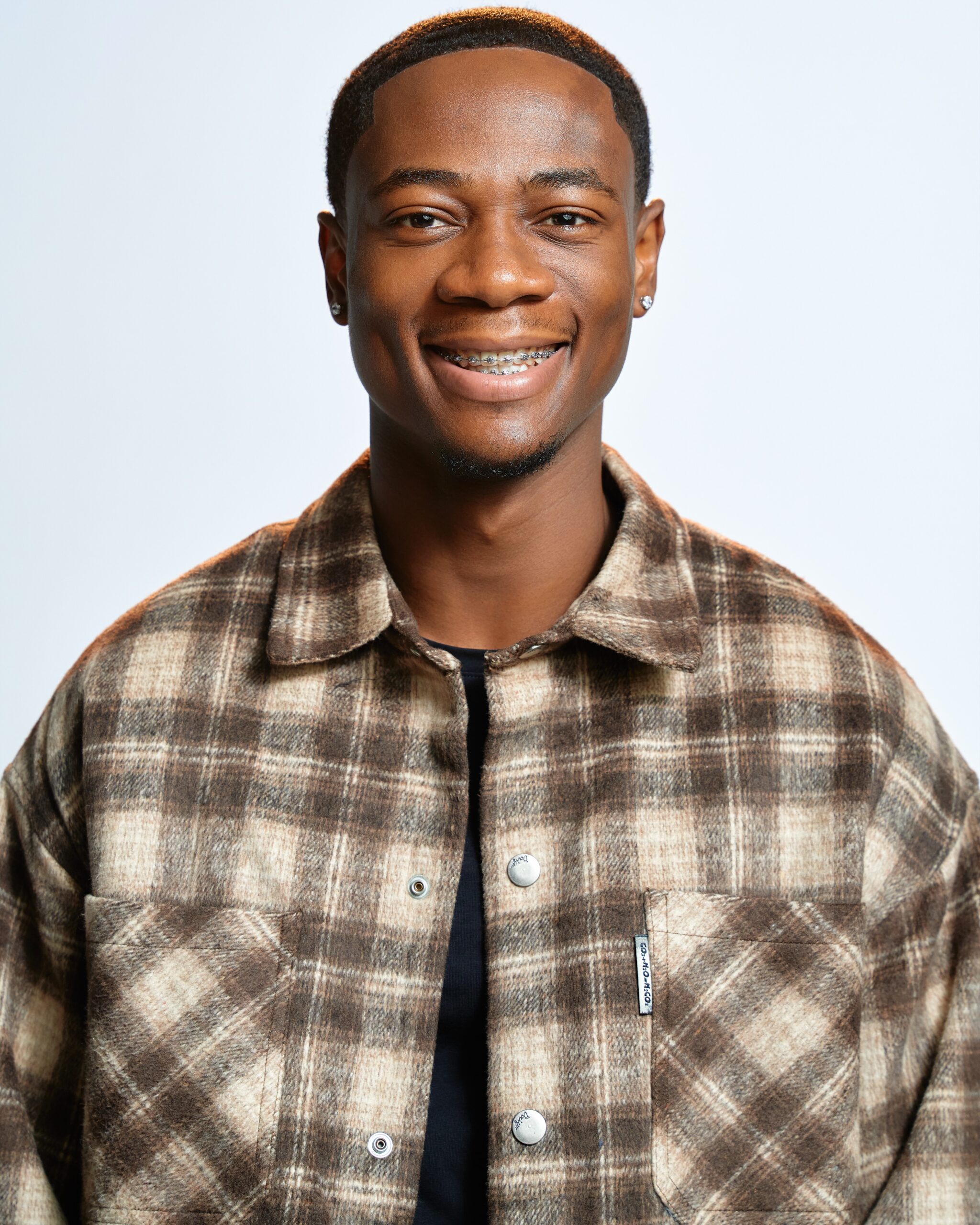 BBNaija Season 11 finalist Tram smiling in a brown patterned shirt