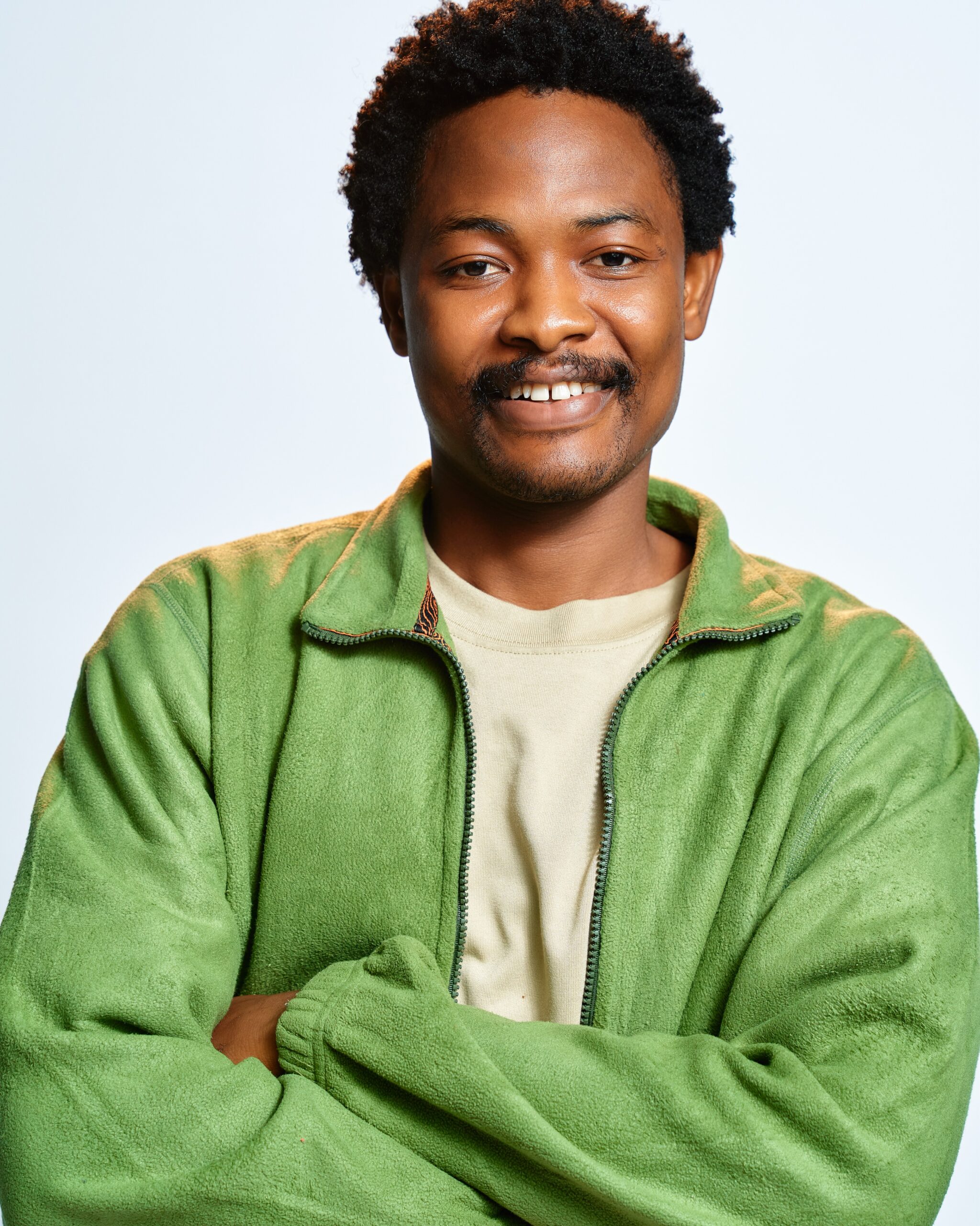 BBNaija Season 11 housemate Aikou smiling with arms crossed in a green jacket
