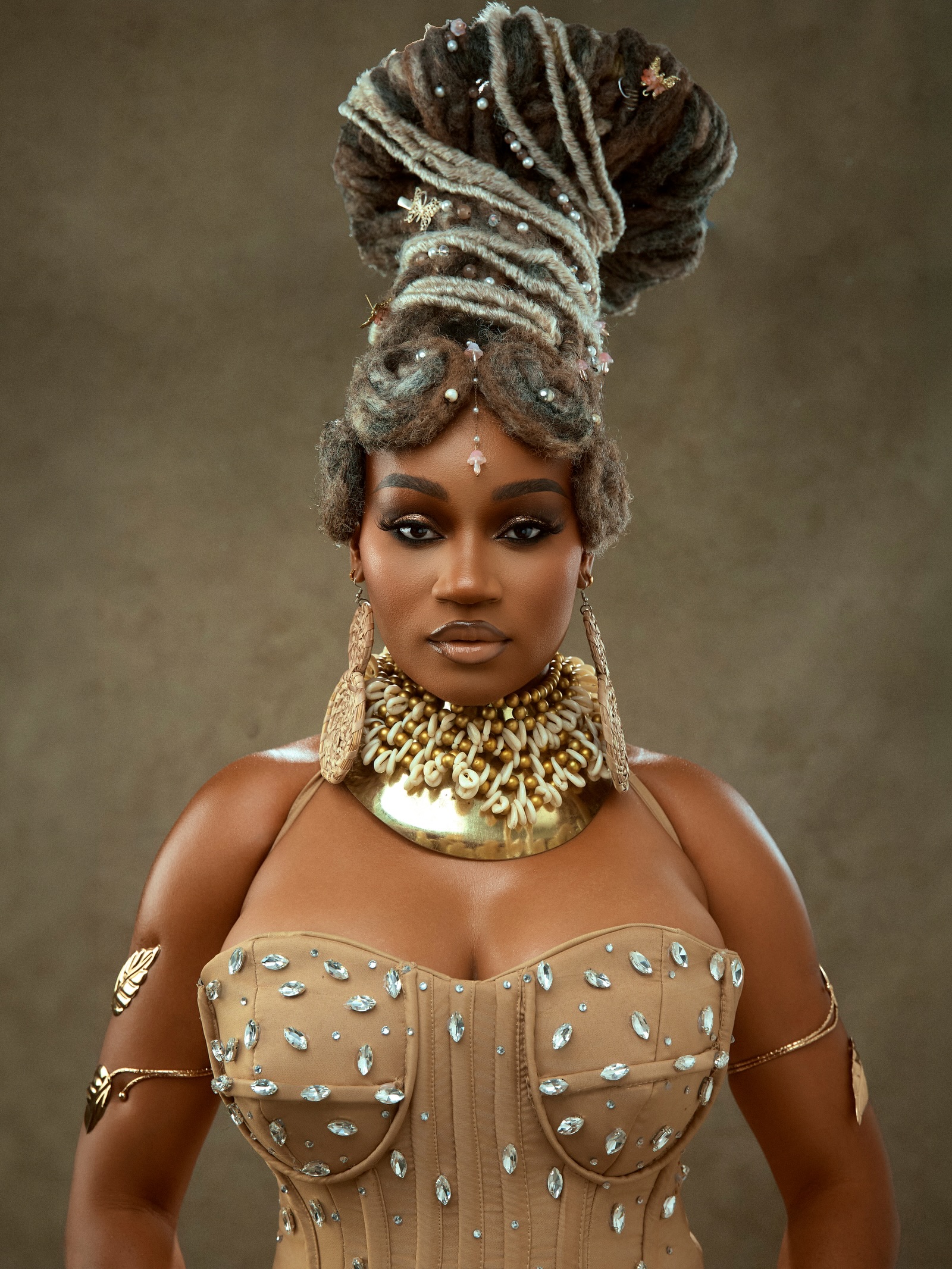 J’Dess wearing a high sculpted locs hairstyle adorned with pearls, a cowrie shell choker, and a crystal-embellished corset top for her ALA EP release.
