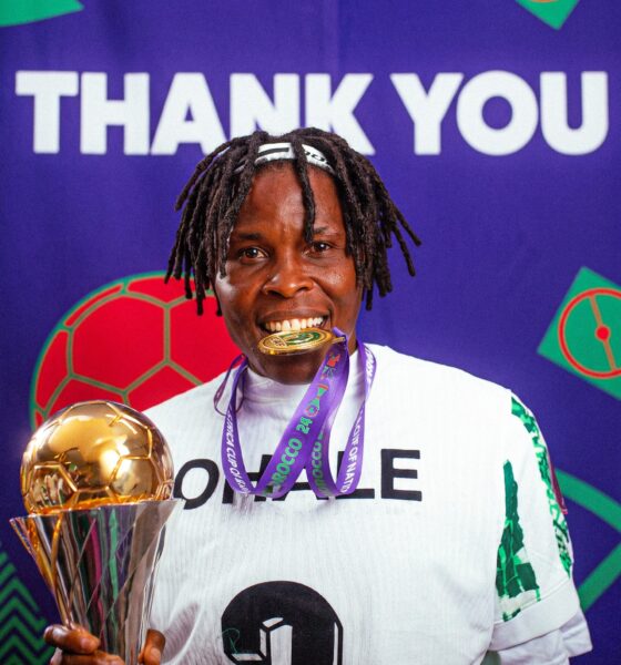 Osinachi Ohale smiling while holding her WAFCON gold medal in front of a Thank You backdrop
