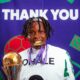 Osinachi Ohale smiling while holding her WAFCON gold medal in front of a Thank You backdrop
