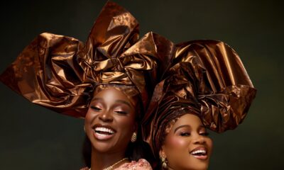 Veekee James and Tomike Adeoye smiling in peach sequin lace blouses, bronze-gold metallic headties, and warm bronzed makeup