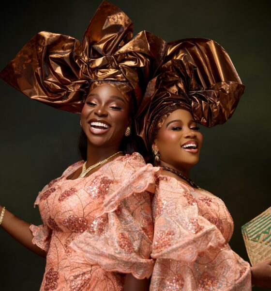 Veekee James and Tomike Adeoye smiling in peach sequin lace blouses, bronze-gold metallic headties, and warm bronzed makeup