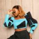 Close framing of Omowunmi Dada showing the black geometric patches and stitching on her turquoise cropped top