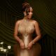 Mercy Eke wearing a custom champagne-bronze silk gown with an exaggerated corset bodice and crystal embellished halter neckline.