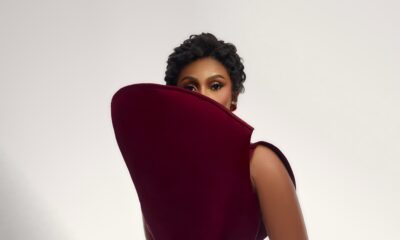Mercy Eke framed by an exaggerated curved shield collar on a maroon top