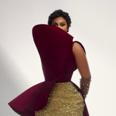 Mercy Eke framed by an exaggerated curved shield collar on a maroon top