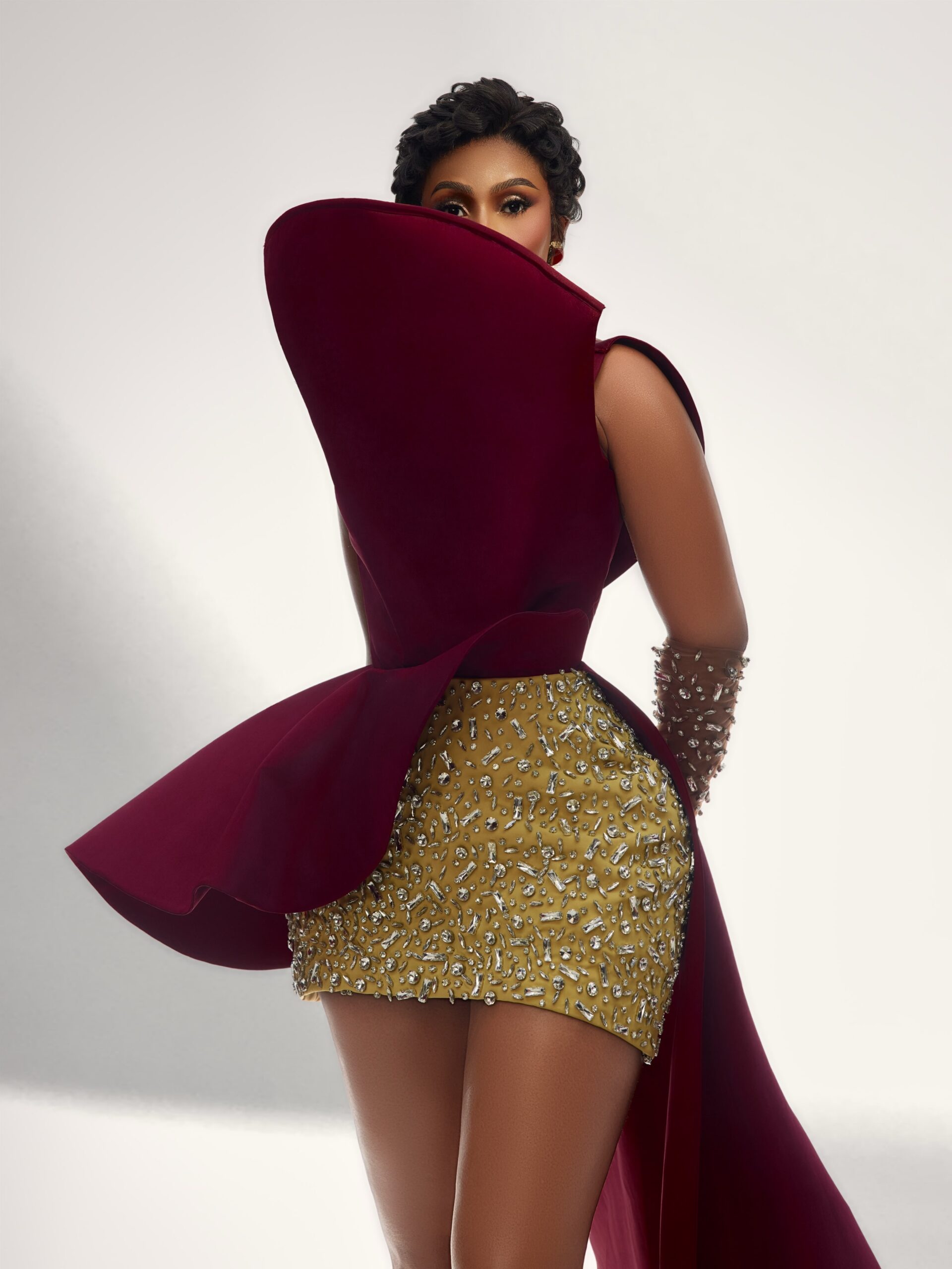 Mercy Eke framed by an exaggerated curved shield collar on a maroon top