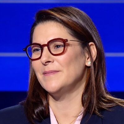 Fatima Ezzahra El Mansouri wearing red frames and a dark blazer