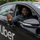 An Uber driver holding an Uber logo sign from inside a black vehicle in Nigeria