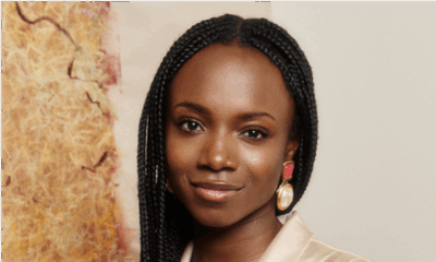 Yinka Ogunbiyi founder of HaloBraid wearing long box braids, statement drop earrings, and a champagne satin blouse.