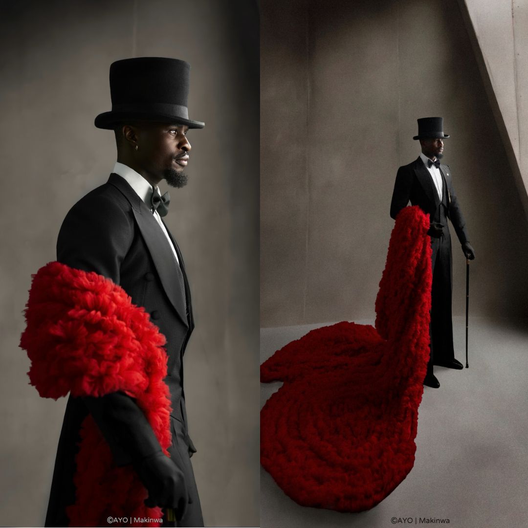 Larry Hector wearing a Victorian black tailcoat, tall top hat, black gloves, and a long crimson red feather boa.