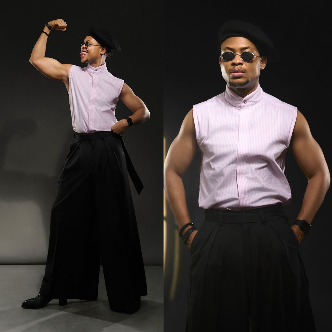 Emeka Nwagbaraocha wearing a sleeveless pink high-collar shirt, black beret, sunglasses, and wide-leg black trousers.
