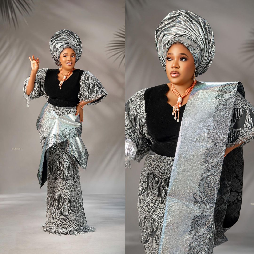 Toyin Abraham Ajeyemi wearing a black velvet top with bell lace sleeves, a silver scalloped-lace skirt, paisley ipele, and coral beads