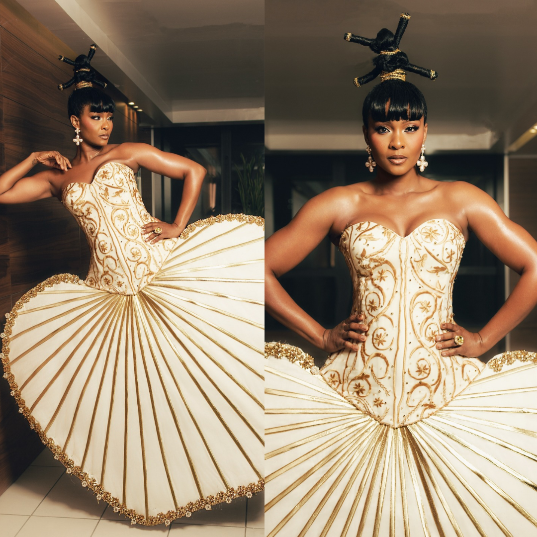 Osas Ighodaro wearing architectural ivory and gold corseted ballgown with pleated fan structure at BellaNaija 20th Anniversary Grand Red Carpet Experience.