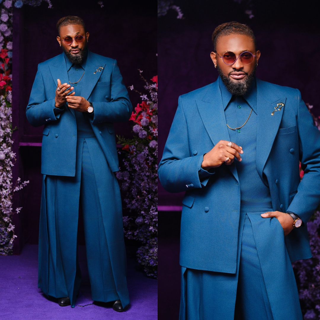 Uti Nwachukwu wearing a monochromatic teal blue double-breasted suit with wide-leg trousers and tinted sunglasses.