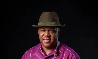 Veteran Nollywood actor Francis Duru wearing a purple striped traditional shirt, fedora hat, and holding a walking stick.