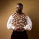 Dr Akin Faminu wearing Mekallia cowrie-shell encrusted vest over billowy white shirt with round sunglasses for The Devil Wears Prada 2 Lagos premiere.