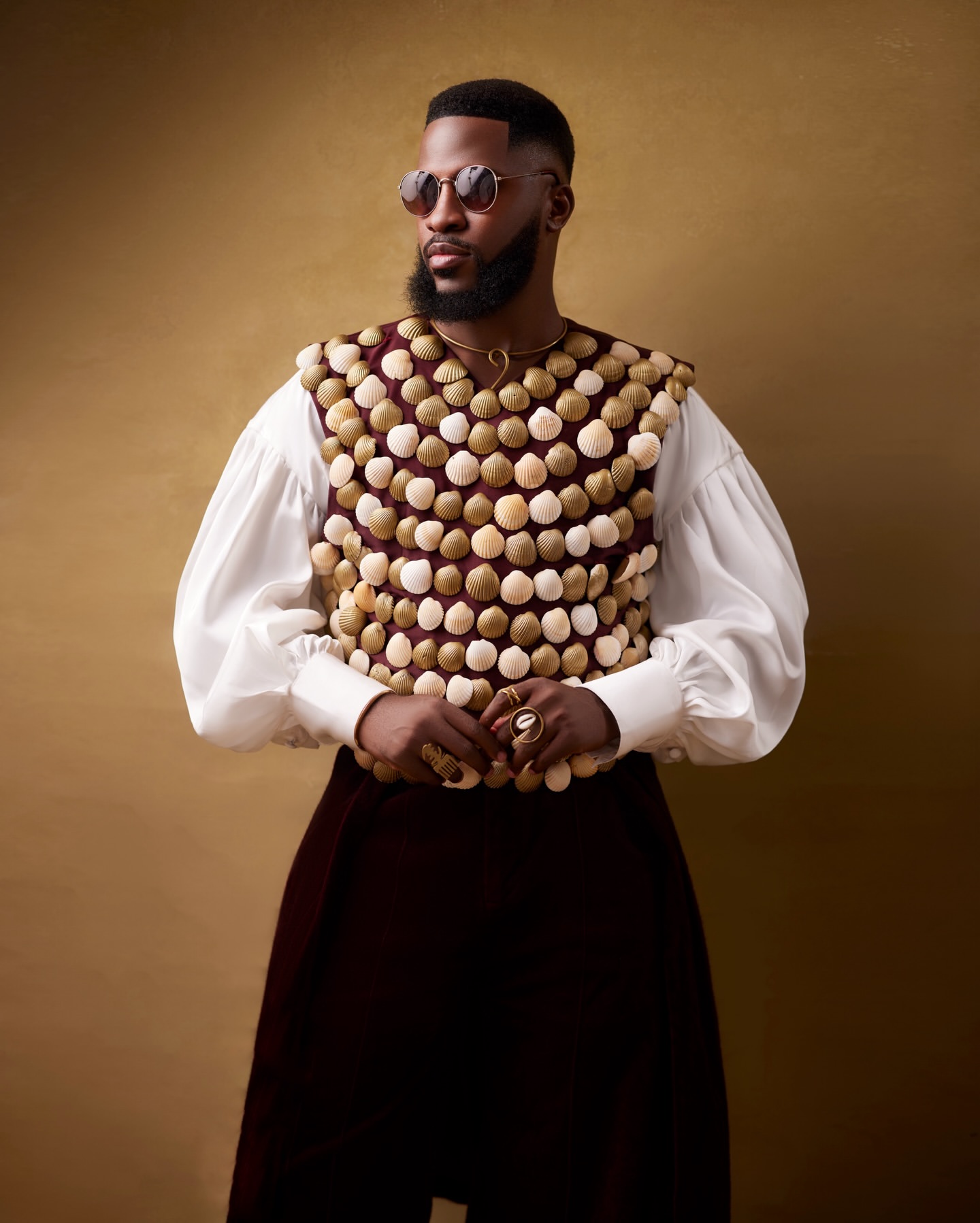 Dr Akin Faminu wearing Mekallia cowrie-shell encrusted vest over billowy white shirt with round sunglasses for The Devil Wears Prada 2 Lagos premiere.