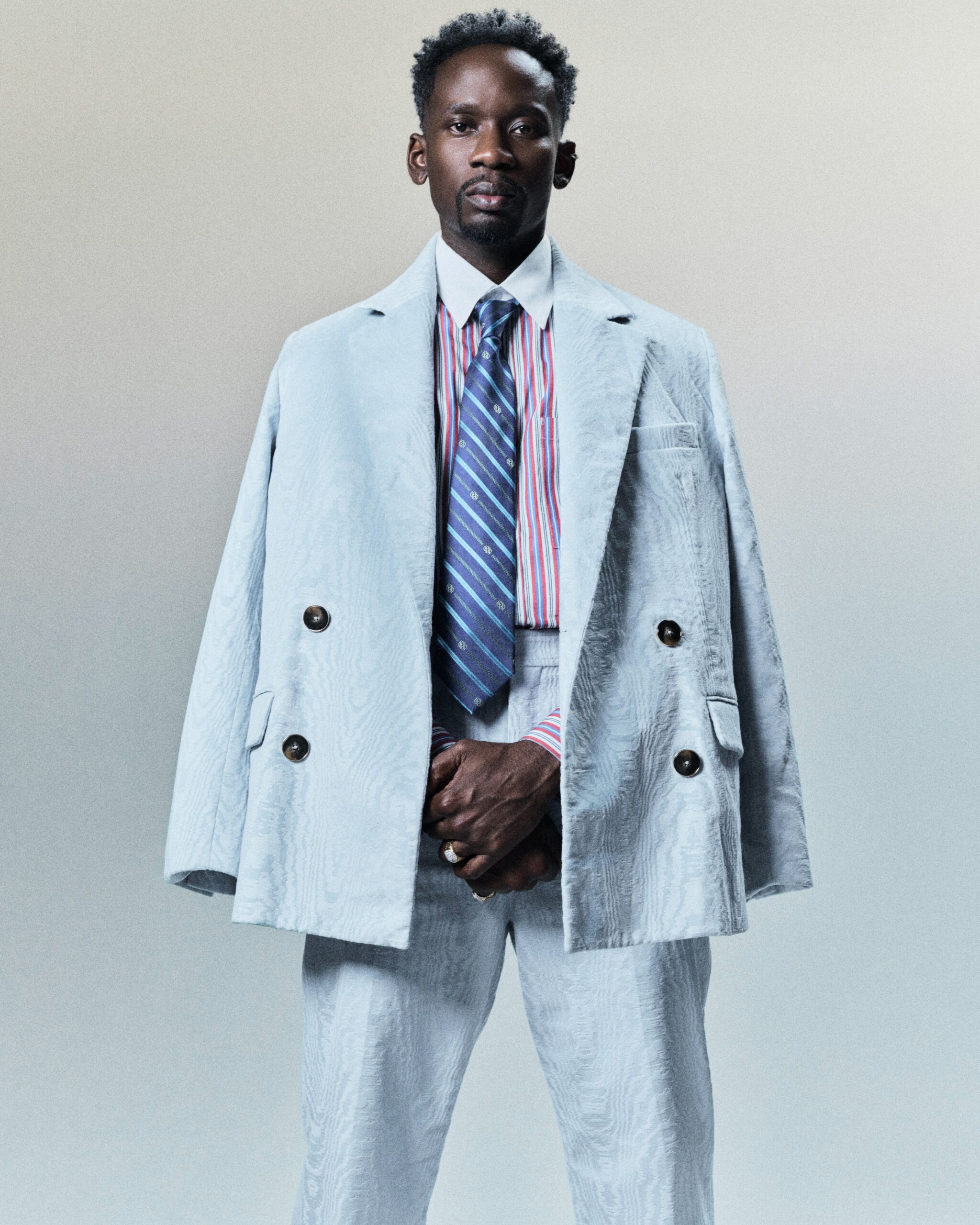 Mr Eazi styled in a light blue double-breasted suit and striped necktie.