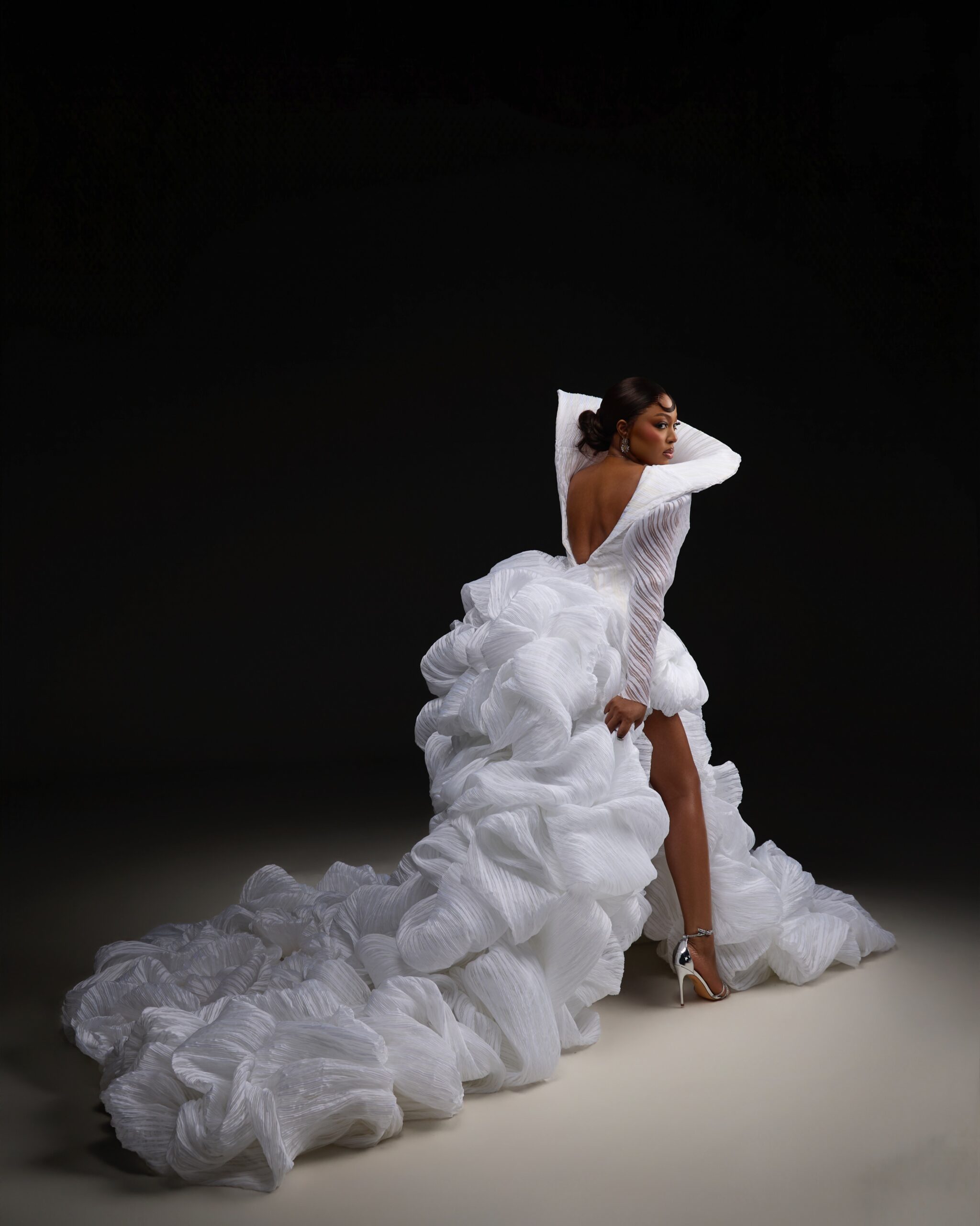 Mide Iwasokun posing in a white structured couture gown by Komeh Swish at the BellaNaija Grand Red Carpet Experience.