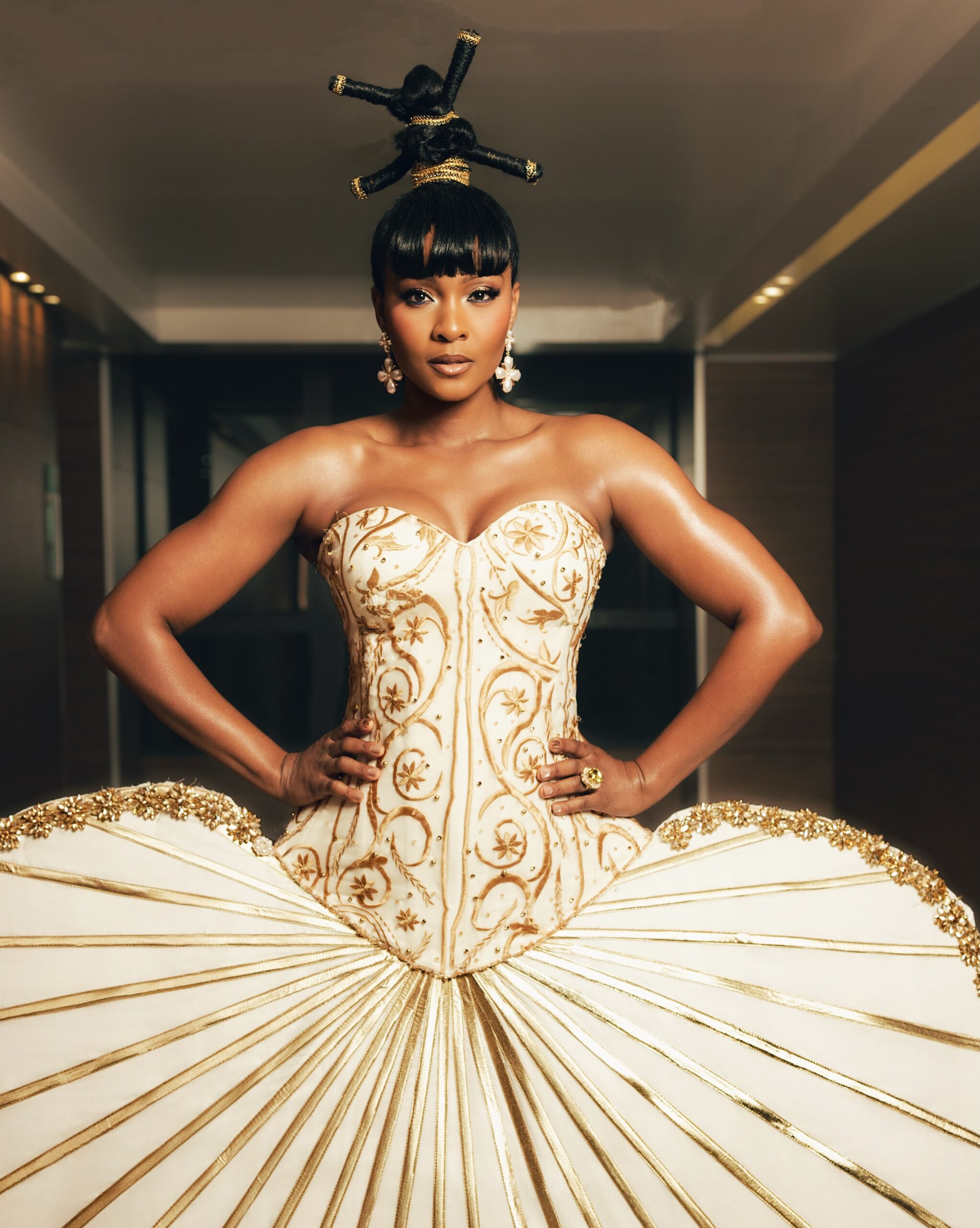 Osas Ighodaro wearing a strapless ivory corset with gold embroidery and threaded updos at the BellaNaija Grand Red Carpet Experience.