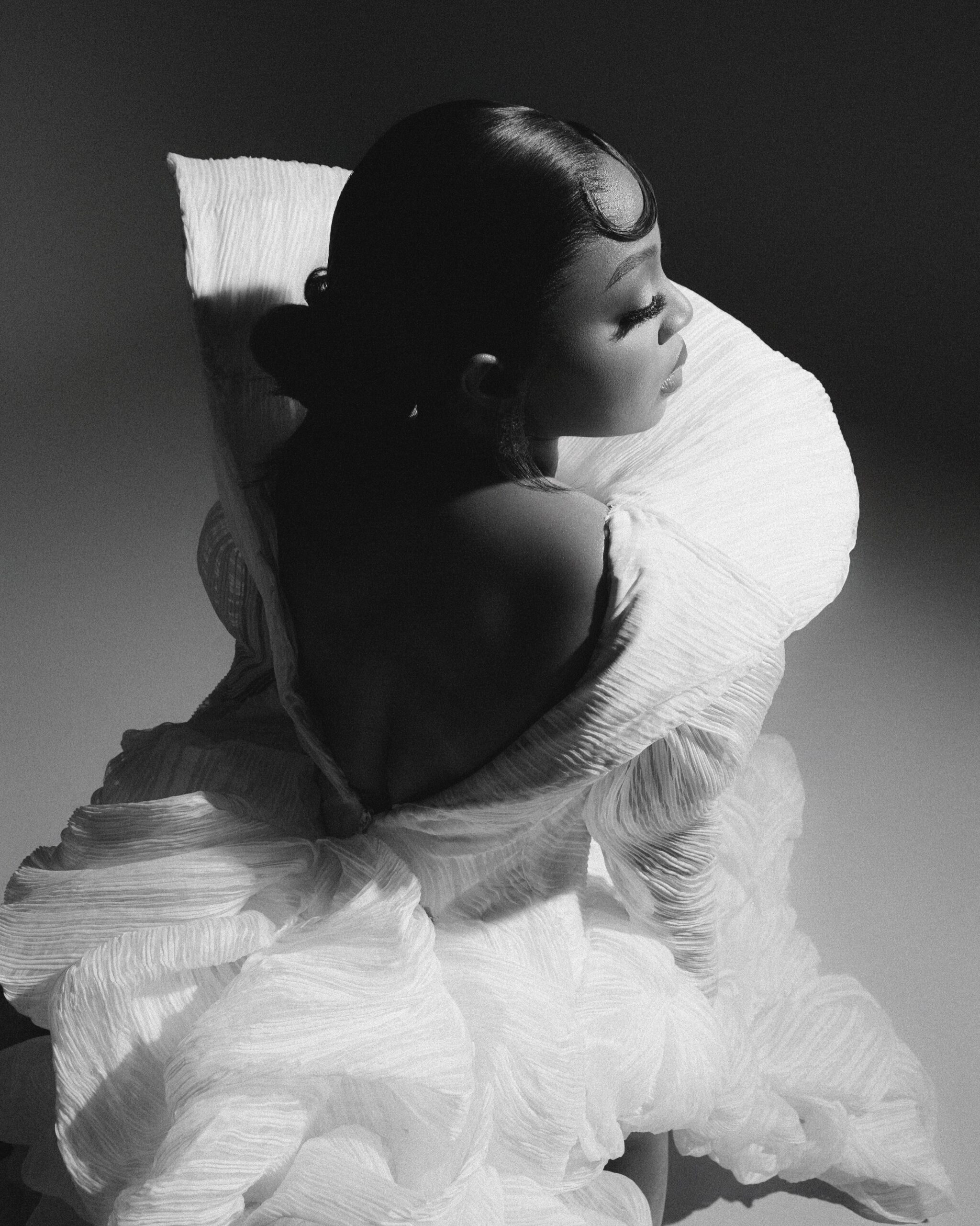 Mide Iwasokun showcasing the open back and exaggerated fan collar of her Komeh Swish gown with a sleek low bun hairstyle