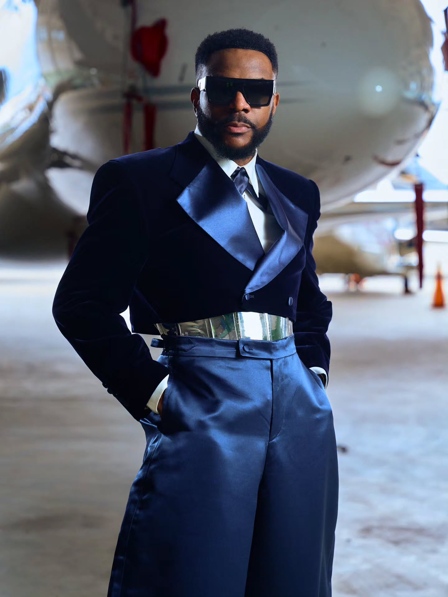 Ebuka Obi-Uchendu with hands in pockets wearing custom Mai Atafo wide-leg satin trousers and cutout dress shoes.