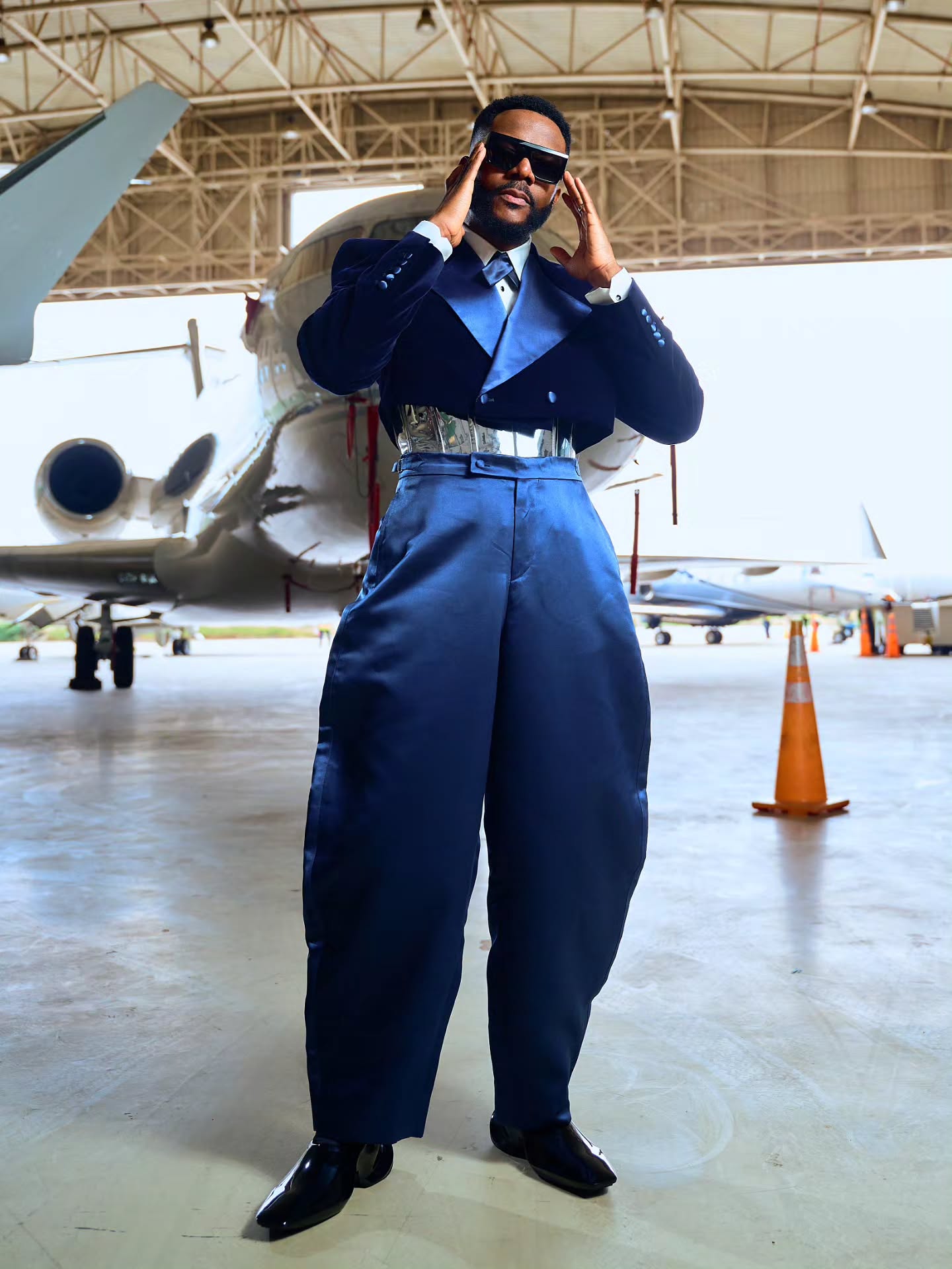 Ebuka Obi-Uchendu adjusting dark sunglasses while wearing a double-breasted Mai Atafo velvet suit.