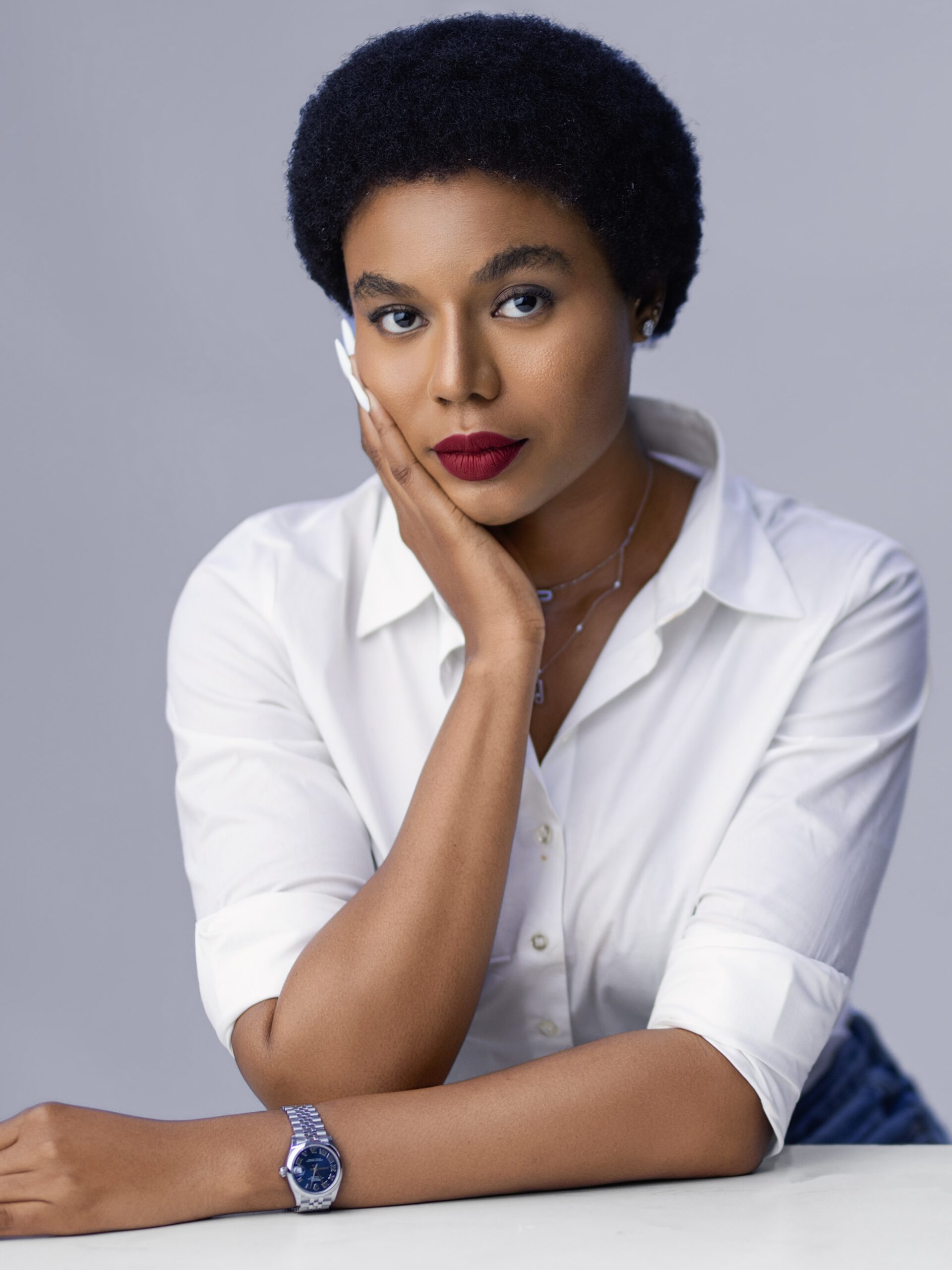 Nollywood actress Nancy Isime wearing a white button-down shirt with a natural afro hairstyle and red lipstick.