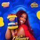 BBNaija Season 11 winner Temi Nkem holding a 2kg jar of Checkers Custard Vanilla Flavour against a blue background.