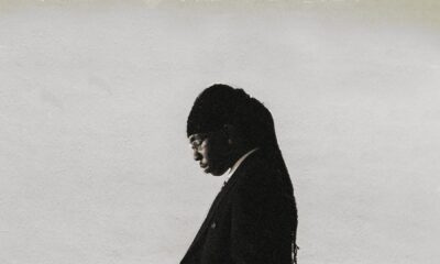 Afrobeats singer FOLA standing in a suit against a monochrome backdrop announcing his sophomore album 9.