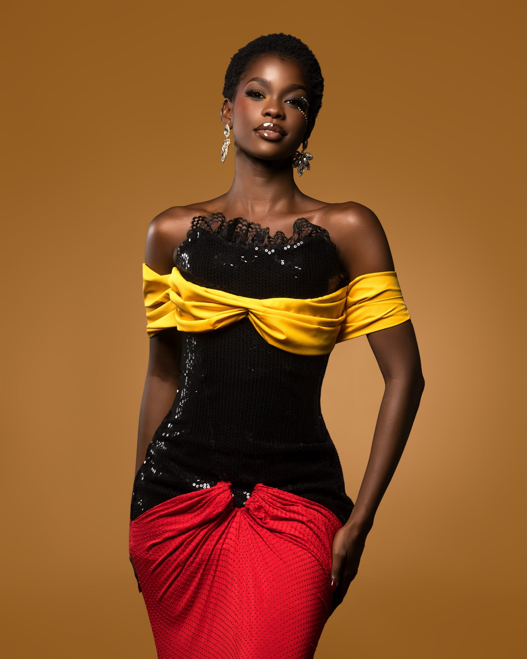 Kimberly Jael in a black sequined corset dress with yellow off-the-shoulder fabric and a ruched red skirt.