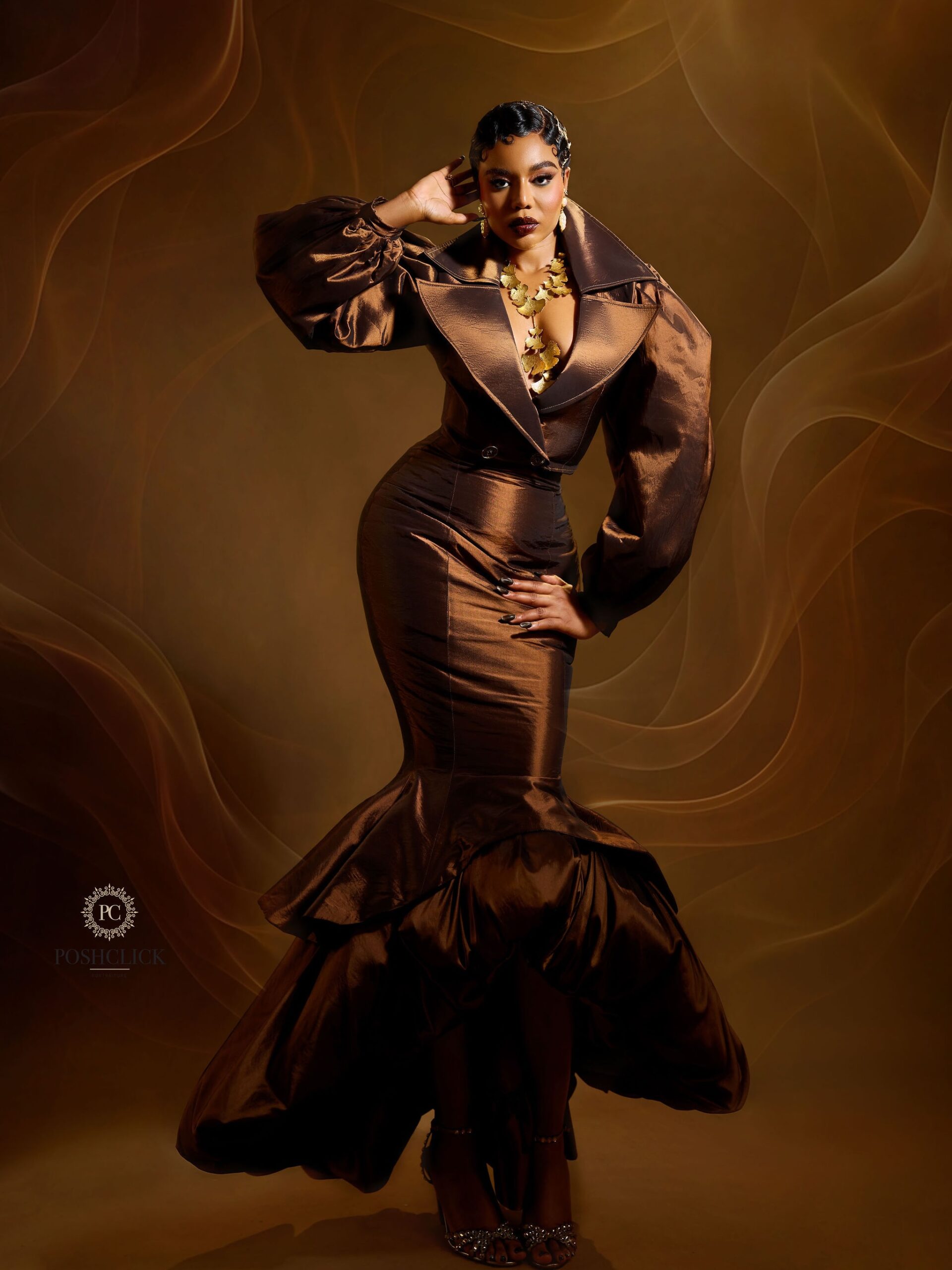 Nancy Isime in a full-length brown mermaid dress with voluminous balloon sleeves for her executive producer announcement video.