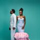 Zlatan Ibile holding hands with Davita Omoniyi against a teal backdrop in pastel ice blue and blush pink outfits.